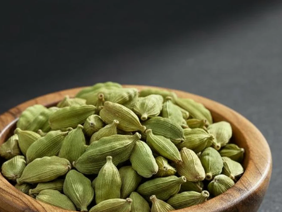 Green cardamom pods in a wooden bowl